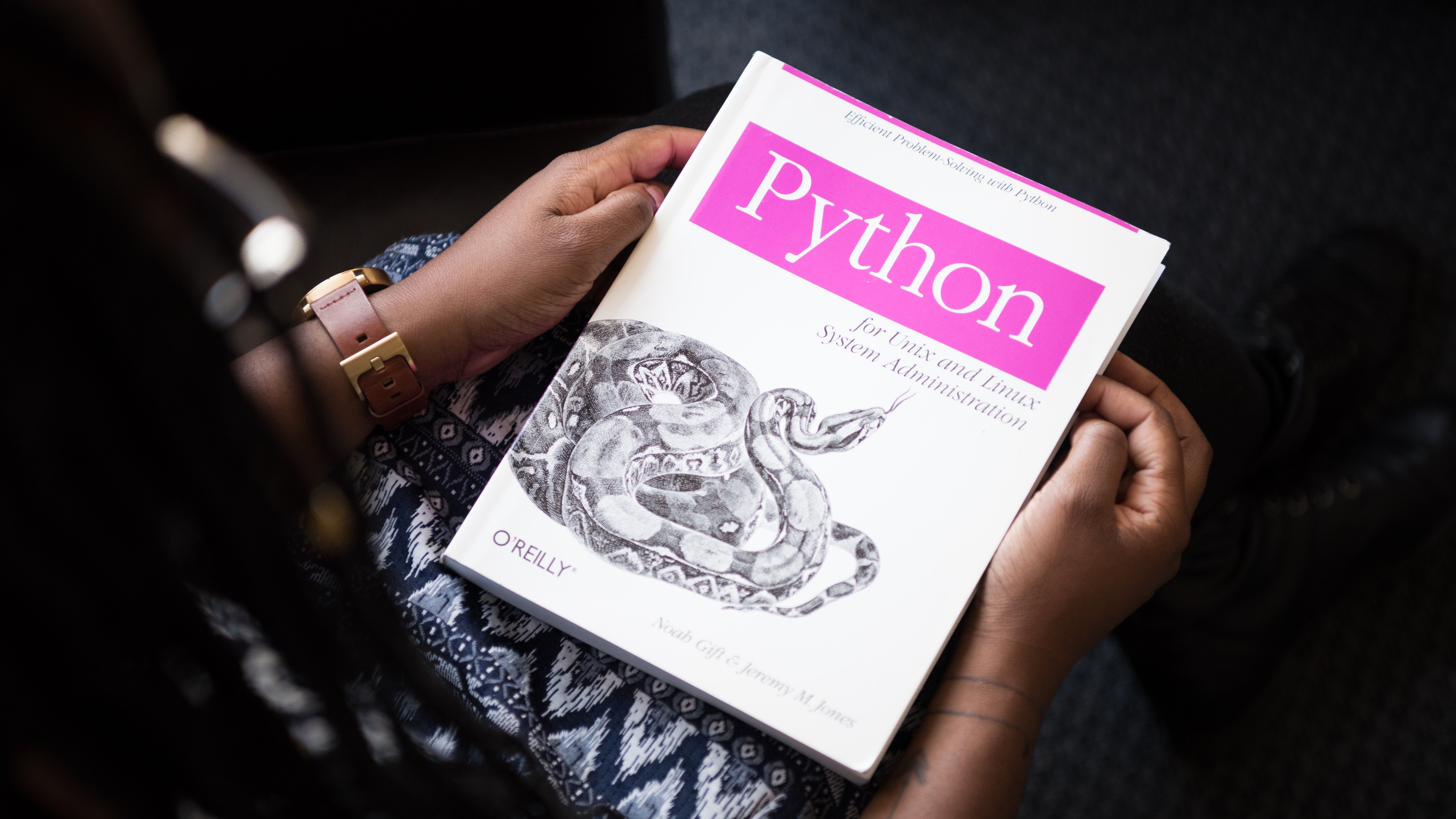 A woman holding a book on Python in her hands